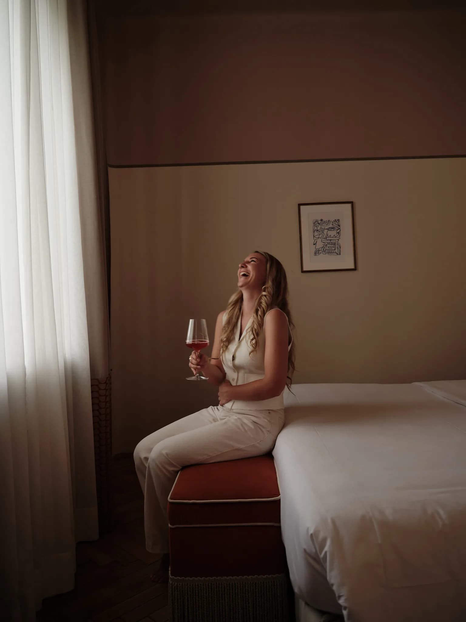 Rosa Besler lacht mit einem Glas Roséwein in der Hand