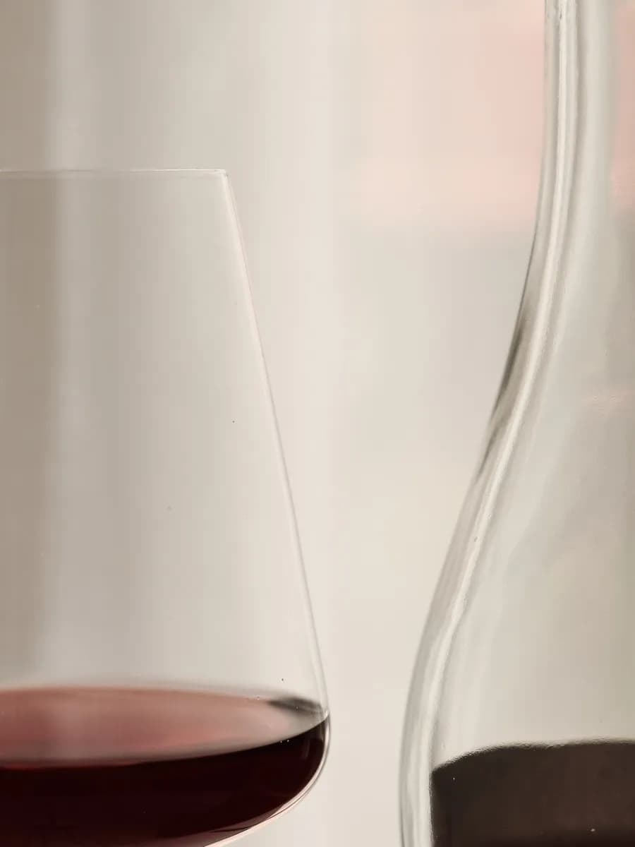 Ein Glas Rotwein neben einer Karaffe im Gegenlicht